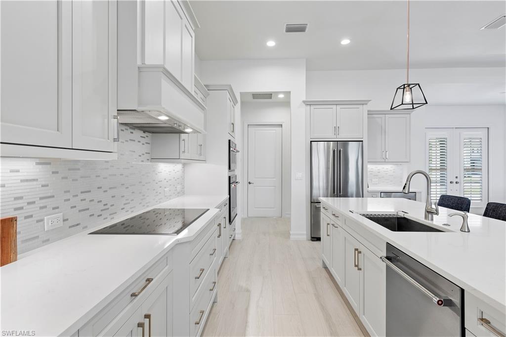 14265 Laguna Springs Lane Naples, FL 34114 - Photo 9 of 40 a kitchen with a sink a counter and stainless steel appliances