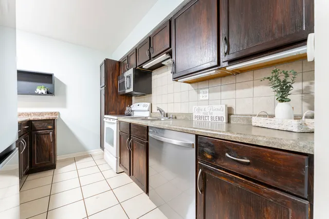 a kitchen with stainless steel appliances granite countertop a stove a sink and a microwave