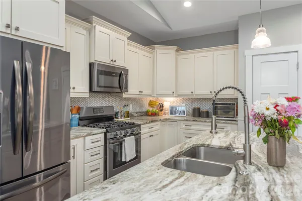 a kitchen with granite countertop a sink stainless steel appliances and cabinets