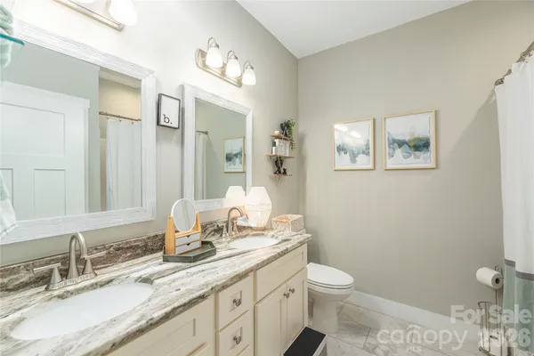 a bathroom with a granite countertop toilet a sink and a mirror