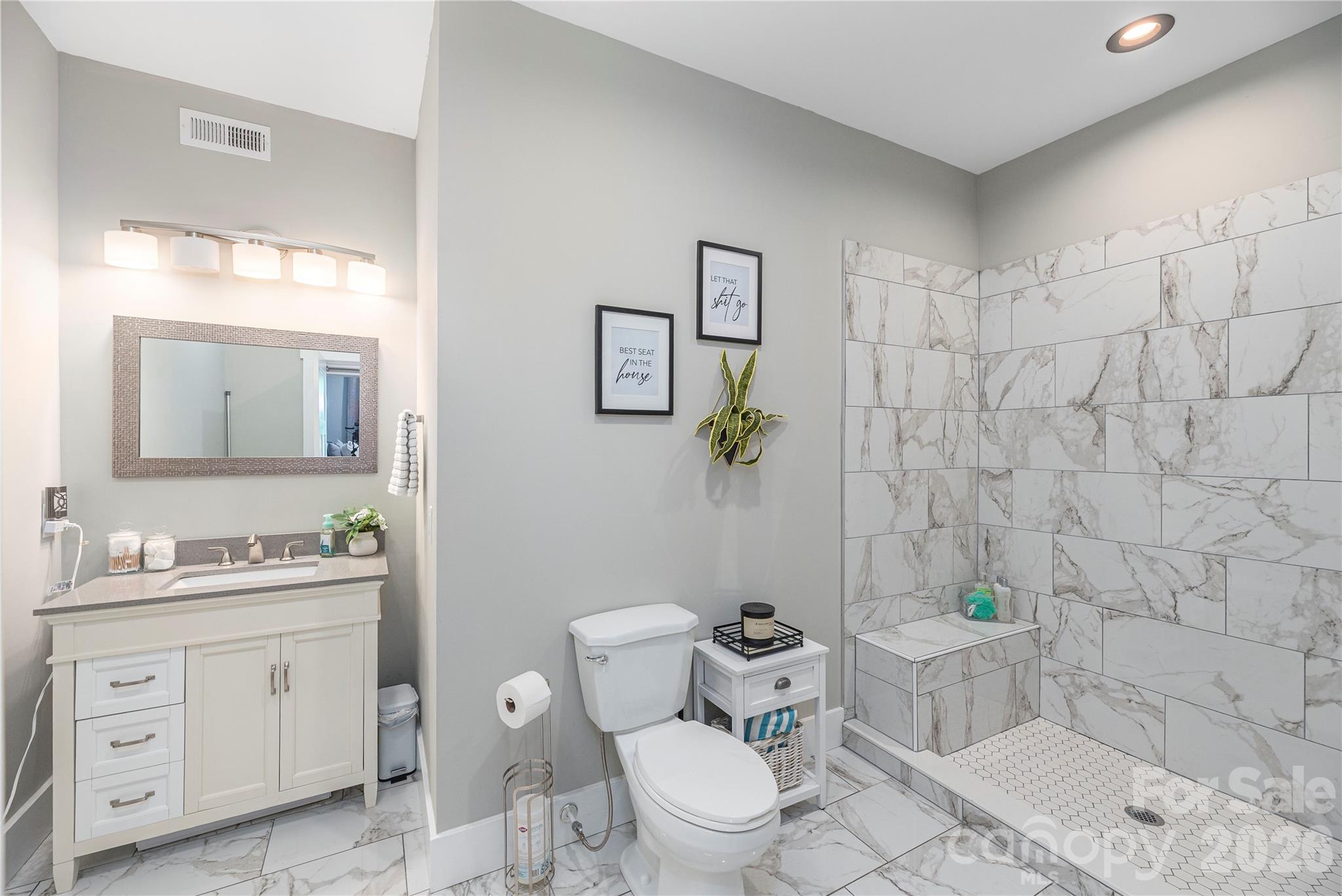 348 Olivet Lane Fletcher, NC 28732 - Photo 32 of 39 a bathroom with a granite countertop toilet a sink a mirror and shower