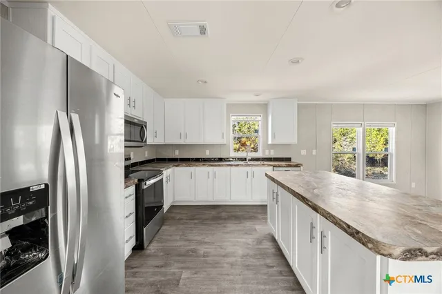 a kitchen with granite countertop a refrigerator and a sink