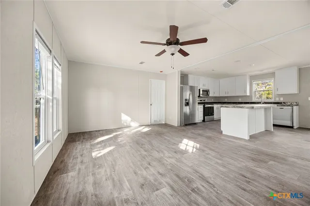 a view of a kitchen with a sink refrigerator and wooden floor