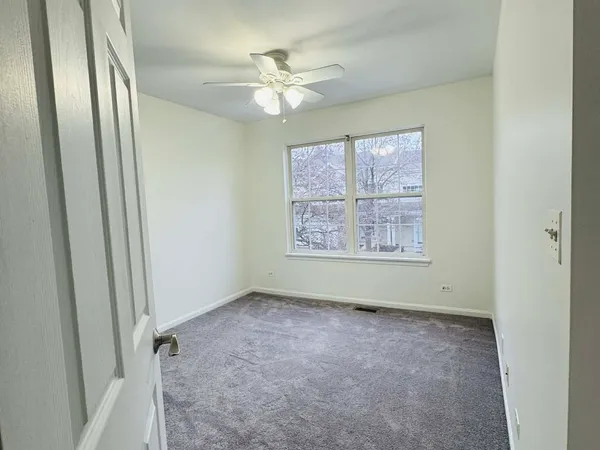 an empty room with windows and fan