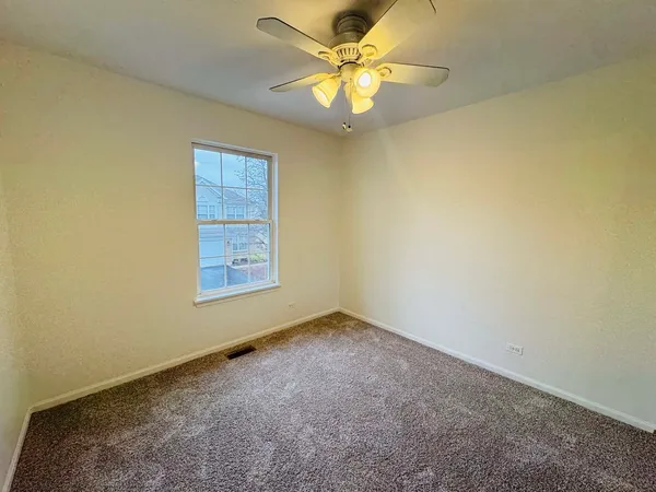 an empty room with a window and a fan