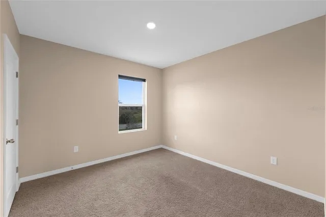 a view of an empty room with window and closet area