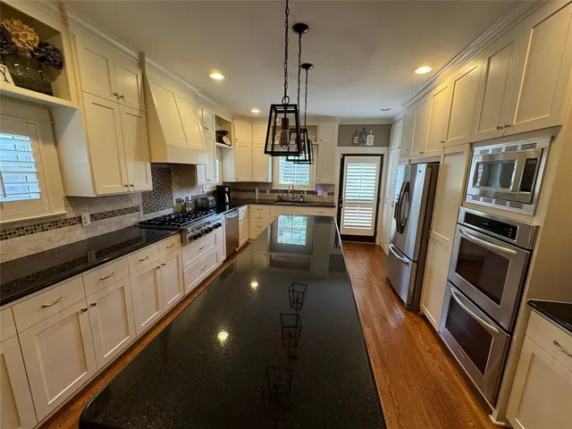 a kitchen with stainless steel appliances granite countertop a refrigerator a stove and a sink