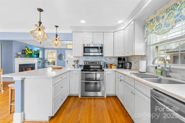 a kitchen with granite countertop a sink cabinets stainless steel appliances and a window