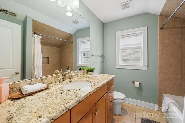 a bathroom with a granite countertop sink a toilet and mirror