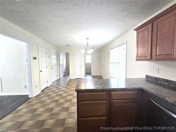 a kitchen with stainless steel appliances granite countertop a refrigerator a sink dishwasher a stove and a dining table with wooden floor