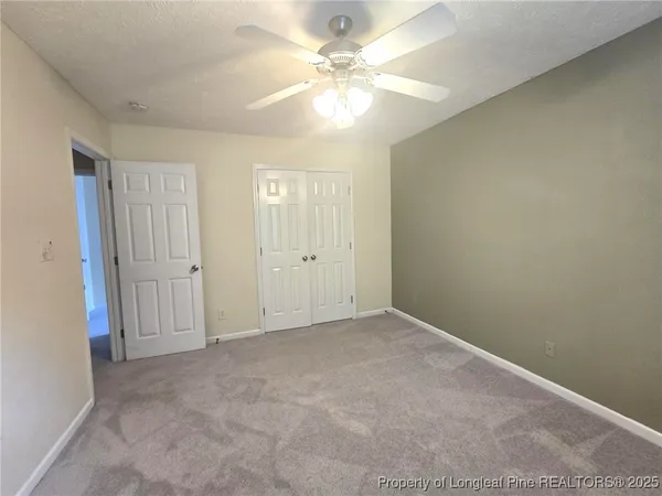 an empty room with a chandelier fan and windows