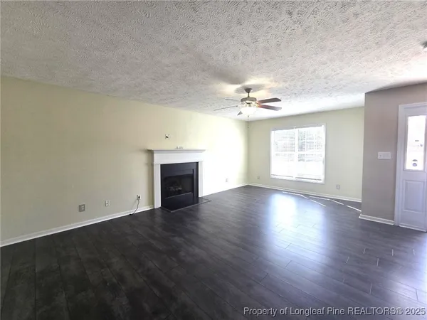 an empty room with wooden floor fireplace and windows