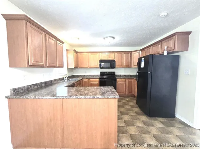 a kitchen with stainless steel appliances granite countertop a refrigerator a stove and a sink with cabinets