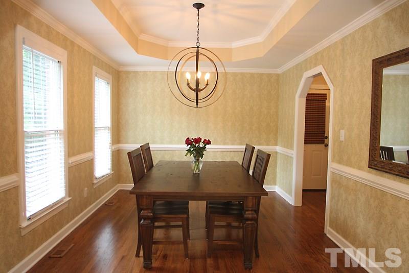 5116 Celbridge Place Raleigh, NC 27613 - Photo 3 of 15 a dining room with wooden floor a chandelier a wooden table and chairs