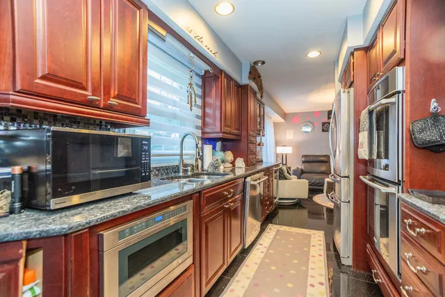 a kitchen with stainless steel appliances granite countertop a stove a sink and a microwave