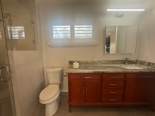 a bathroom with a granite countertop toilet a sink and a mirror