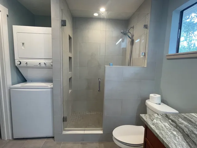 a bathroom with a granite countertop toilet and a shower