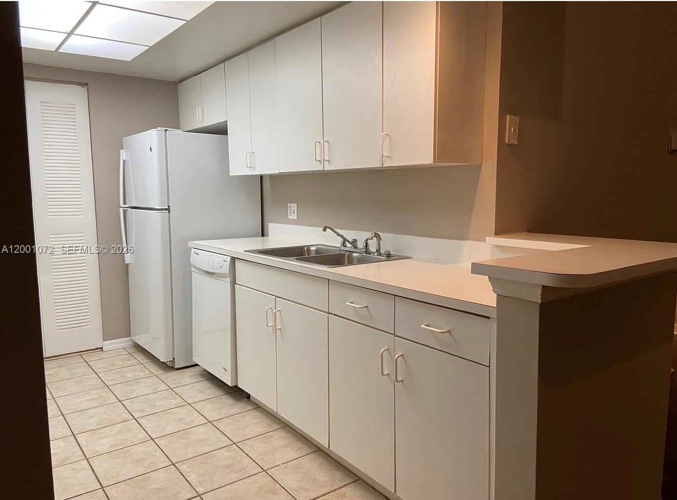 4167 Haverhill Road, Unit 1113 West Palm Beach, FL 33417 - Photo 7 of 19 a kitchen with a sink refrigerator and cabinets