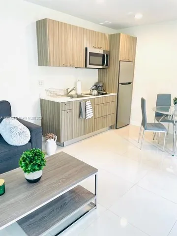 a kitchen with stainless steel appliances kitchen island granite countertop a table chairs and a refrigerator