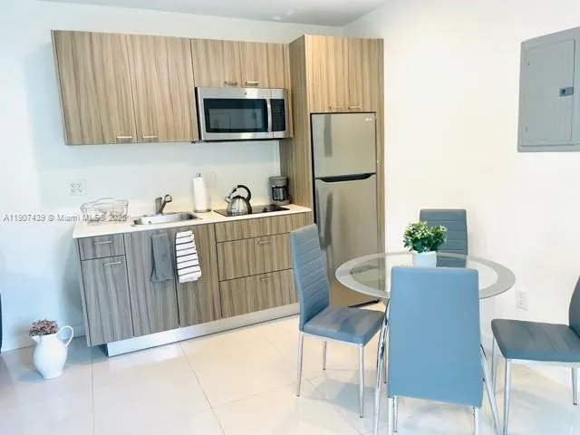 a living room with stainless steel appliances kitchen island granite countertop furniture a refrigerator and a microwave