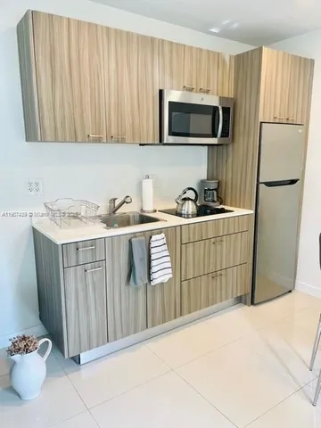 a kitchen with a sink a microwave a refrigerator and cabinets