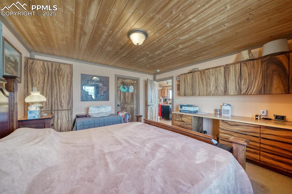 565 Pass Peak Road Westcliffe, CO 81252 - Photo 13 of 50 a large bedroom with a large bed and a chandelier