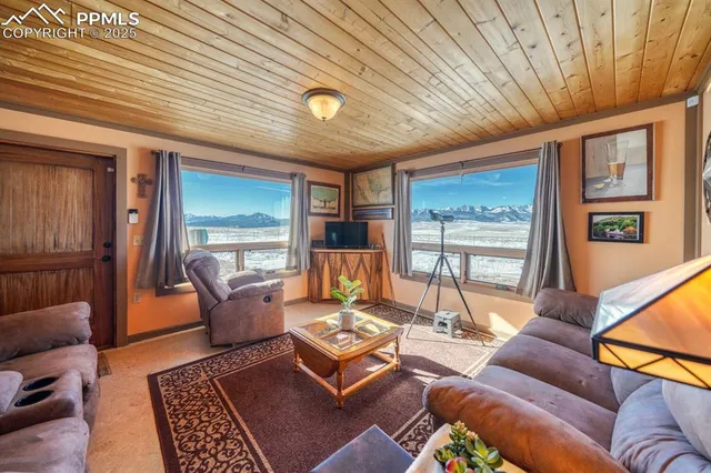 a living room with furniture a rug kitchen view and a large window
