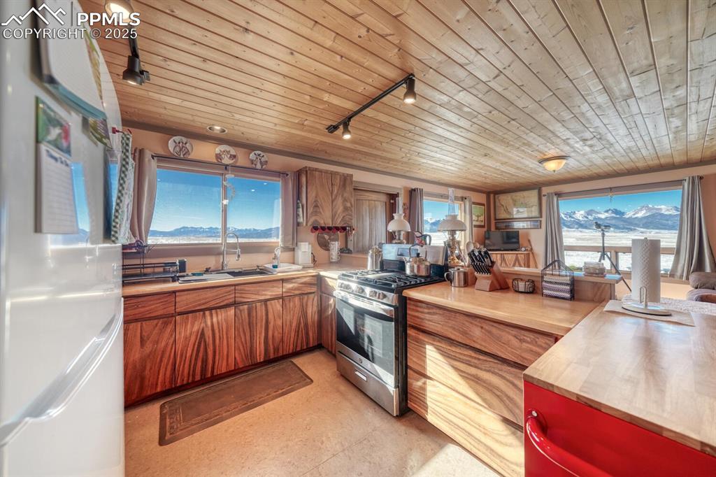 565 Pass Peak Road Westcliffe, CO 81252 - Photo 7 of 50 a large kitchen with stainless steel appliances wooden cabinets a stove and a sink