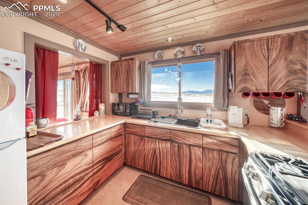 565 Pass Peak Road Westcliffe, CO 81252 - Photo 8 of 50 a kitchen with stainless steel appliances granite countertop a sink and wooden cabinets