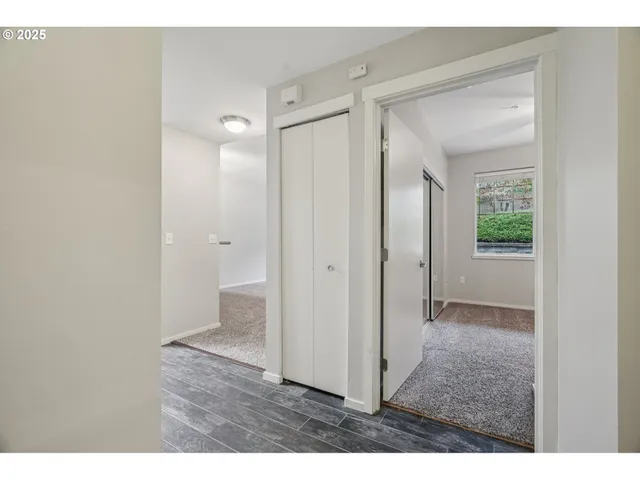 a view of an empty room with wooden floor and a bathroom