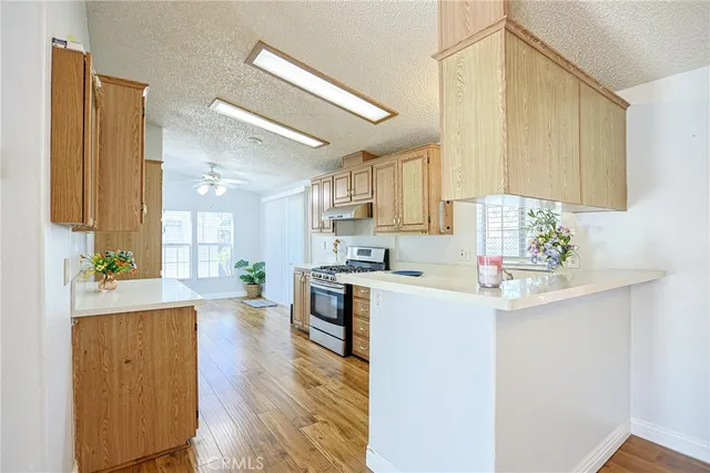 a kitchen with stainless steel appliances a sink a stove a refrigerator cabinets and a window
