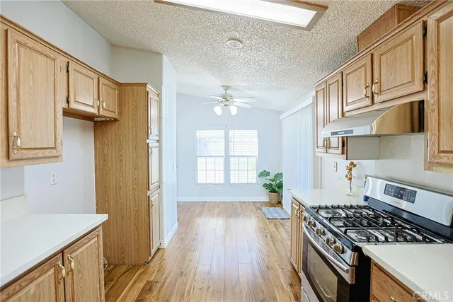 a kitchen with stainless steel appliances a stove a sink a refrigerator cabinets and wooden floor