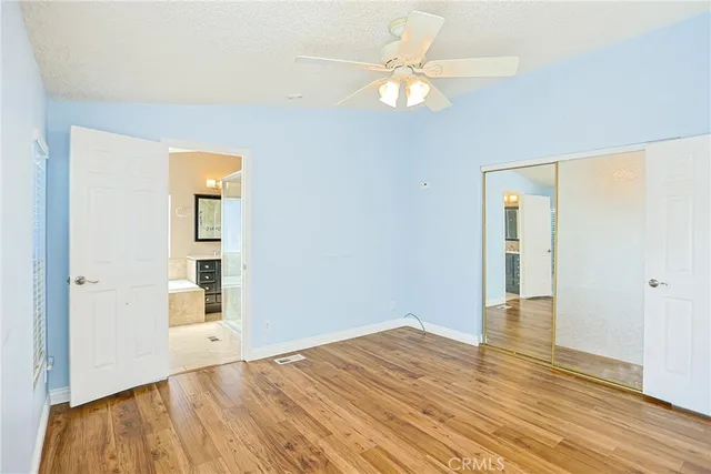 an empty room with wooden floor mirror and windows