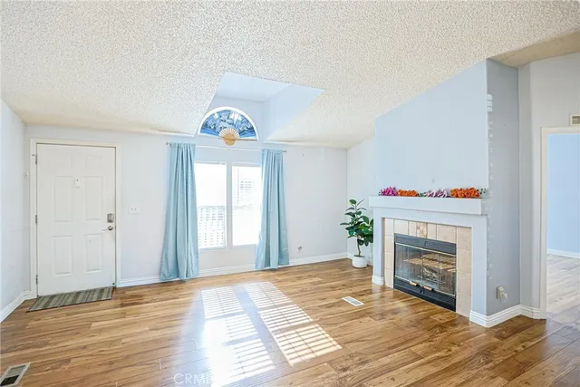 a view of an empty room with wooden floor and a fireplace
