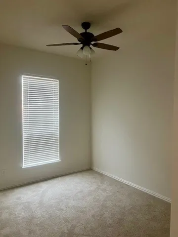 an empty room with a window and a fan