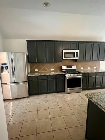 a kitchen with stainless steel appliances granite countertop a stove a sink and a refrigerator