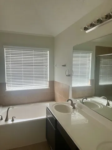 a bathroom with a tub sink and mirror