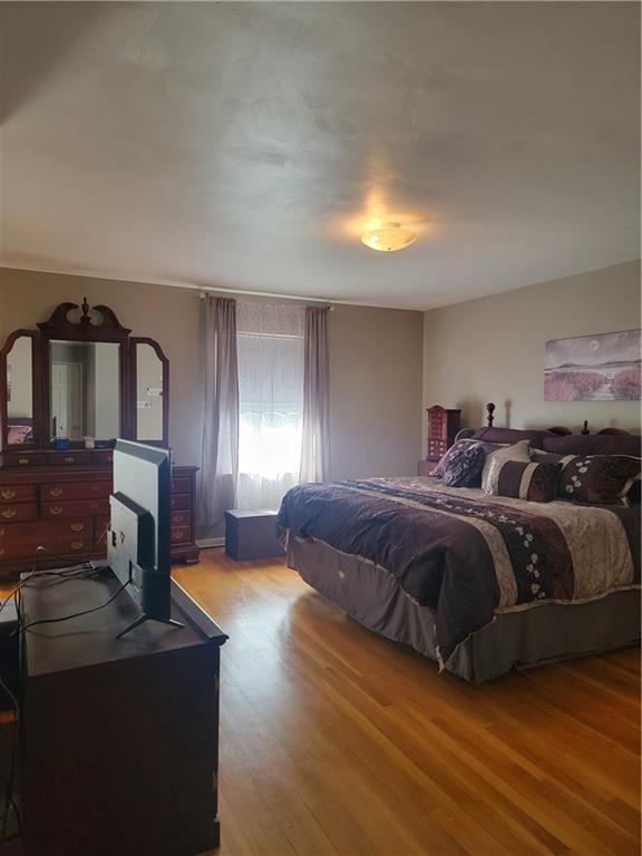 414 Hancock Avenue Vandergrift, PA 15690 - Photo 14 of 16 a spacious bedroom with a bed a mirror on dresser and a chandelier