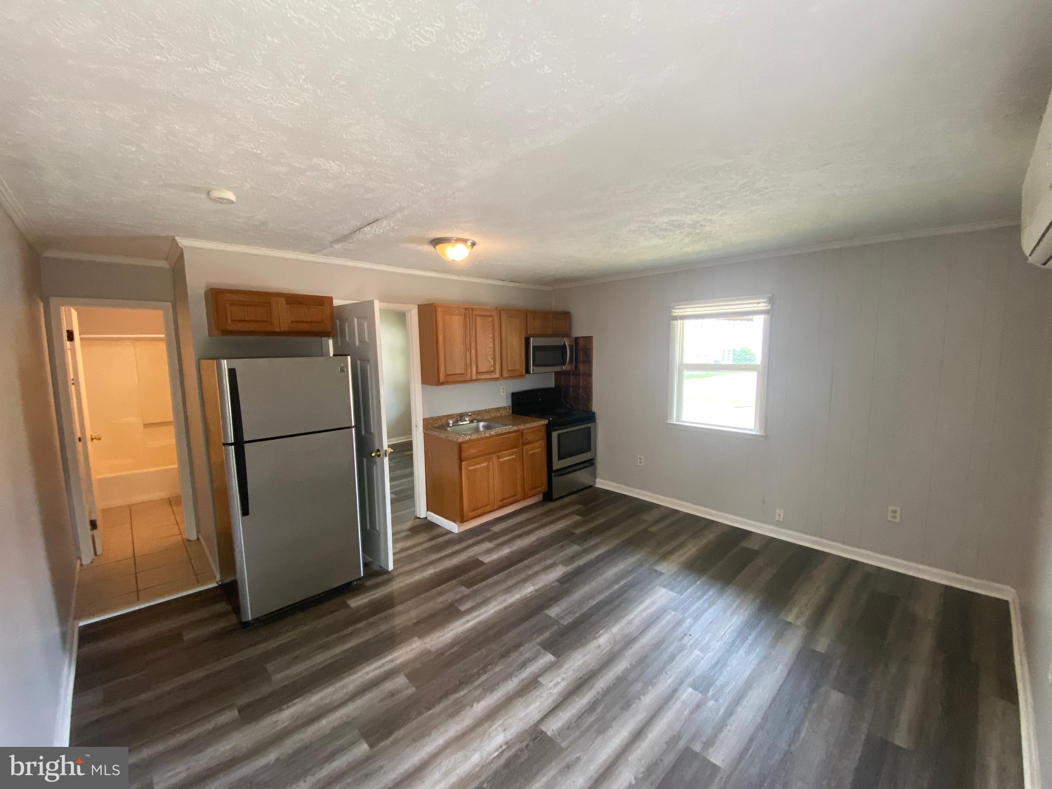 201 North Irving Avenue, Unit D Colonial Beach, VA 22443 - Photo 3 of 10 a view of a kitchen with a fridge wooden floor and a window