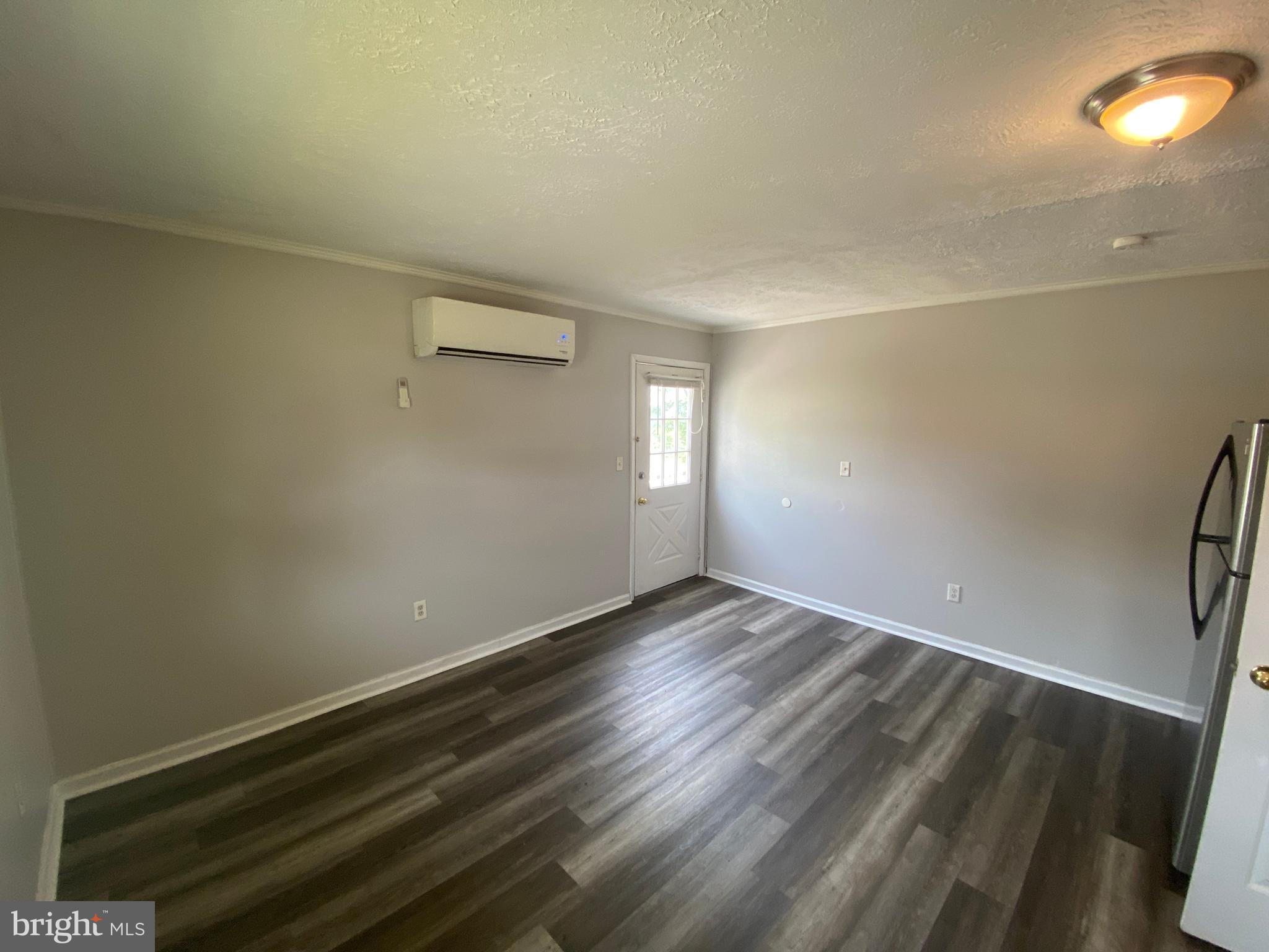 201 North Irving Avenue, Unit D Colonial Beach, VA 22443 - Photo 5 of 10 a view of an empty room with wooden floor and a window