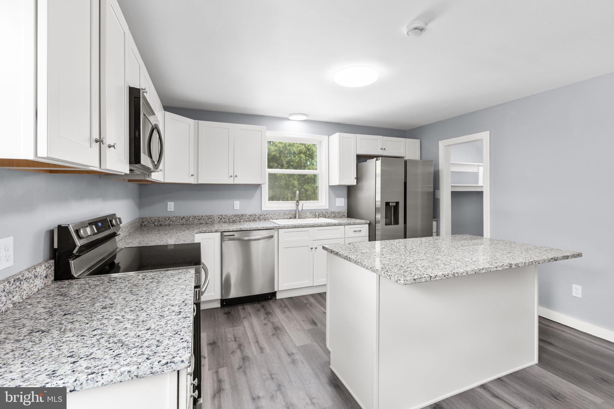 9113 Thornton Rolling Road Fredericksburg, VA 22408 - Photo 5 of 31 a kitchen with kitchen island granite countertop a sink cabinets and stainless steel appliances