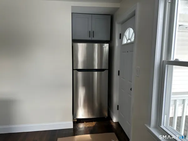 a view of empty room with windows and refrigerator