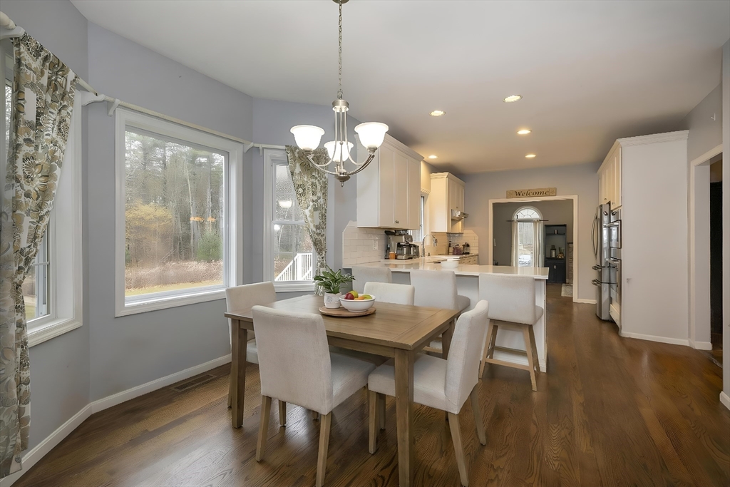 142 River Road Pepperell, MA 01463 - Photo 12 of 41 a dining room with wooden floor a chandelier a wooden table and chairs