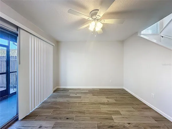 a view of an empty room with wooden floor and a kitchen