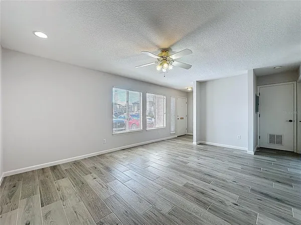a view of an empty room with a window and wooden floor