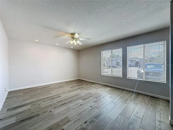 a view of an empty room with a window and a kitchen