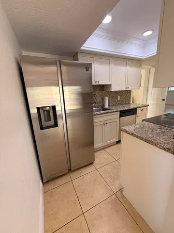 a kitchen with stainless steel appliances granite countertop a refrigerator a sink a stove top oven and a dishwasher