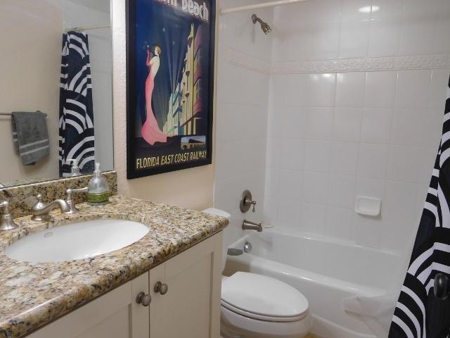 6797 Northeast 7th Avenue Boca Raton, FL 33487 - Photo 13 of 21 a bathroom with a granite countertop sink a toilet and bathtub