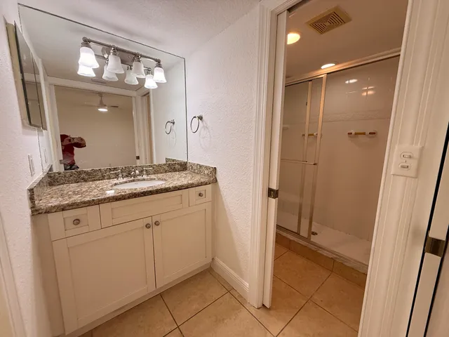a bathroom with a granite countertop sink a mirror and a shower