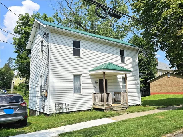a view of a white house with a yard and plants